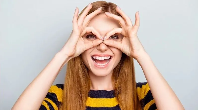 Vrolijke vrouw die met haar handen een bril vormt na ooglaseren